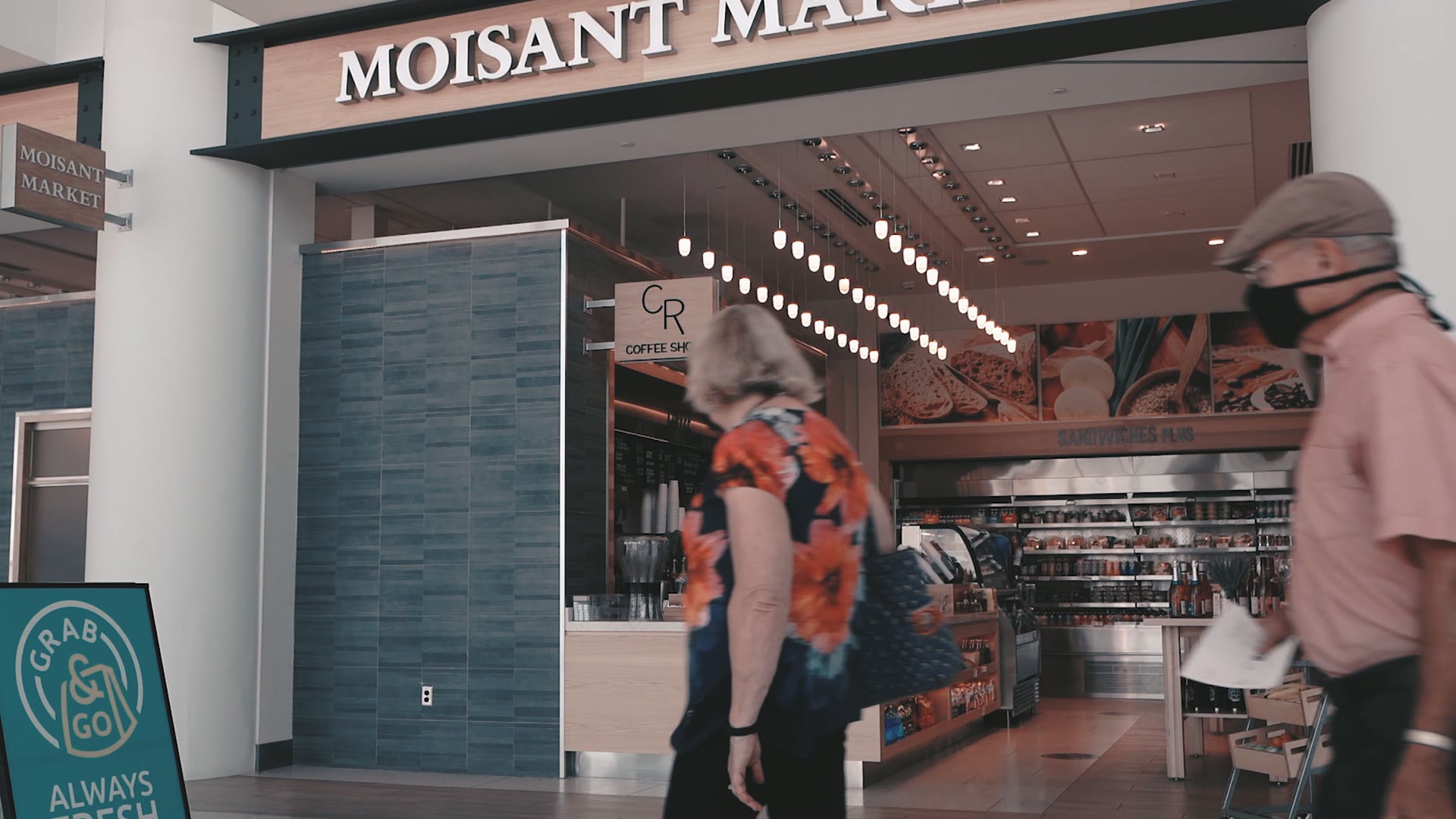 A traveler walking into Moisant Market past the CR Coffee kiosk