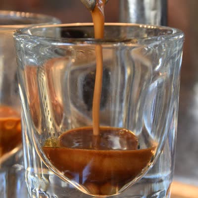 A double shot of espresso pouring into a glass