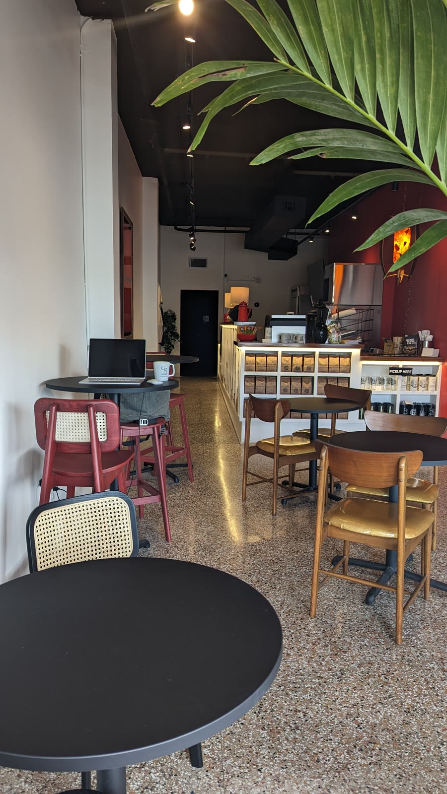Inside CR Coffee Old Metairie, from the front tables back to the counter and retail wall