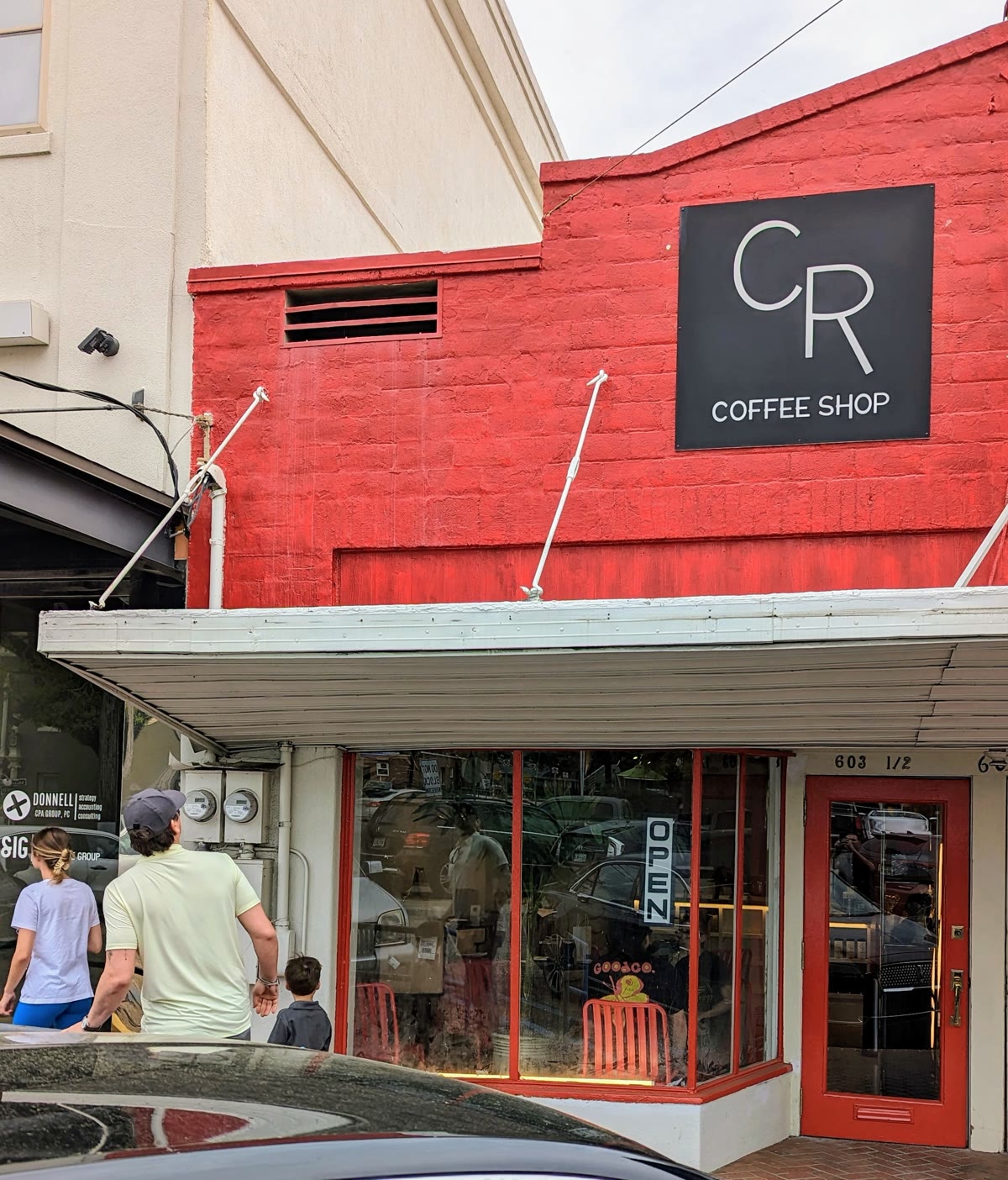 Neighbors walking past the red brick CR Coffee storefront on Metairie Road