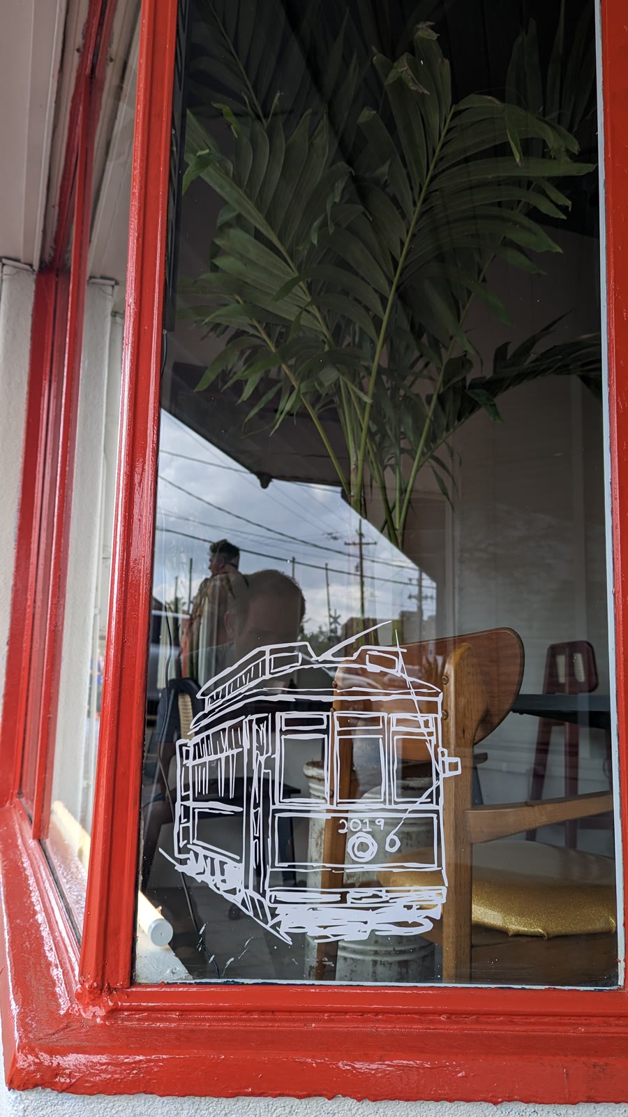 The hand-drawn streetcar decal on the corner window at CR Coffee Old Metairie