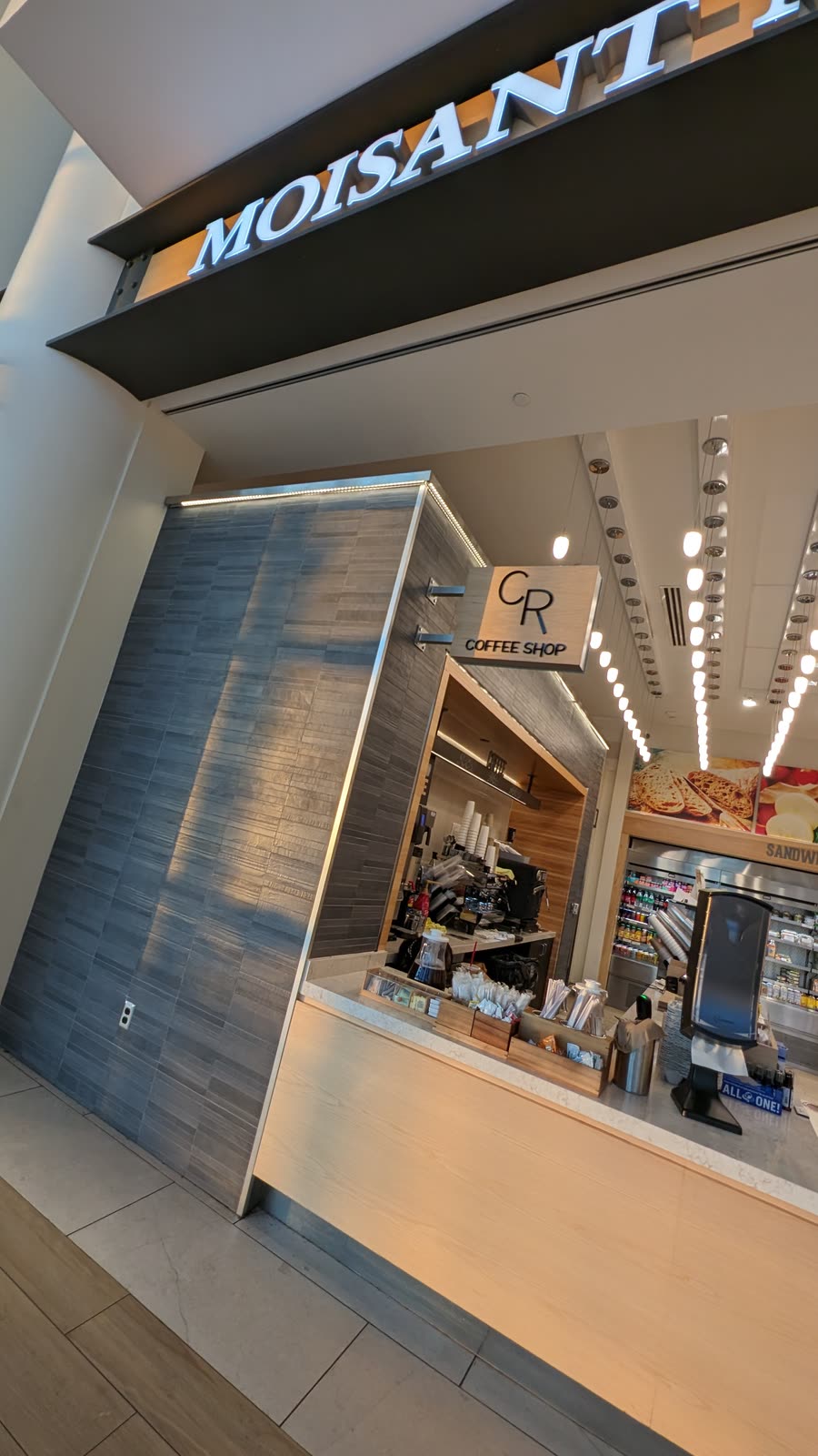 The CR Coffee kiosk seen from the concourse, under the terminal lights