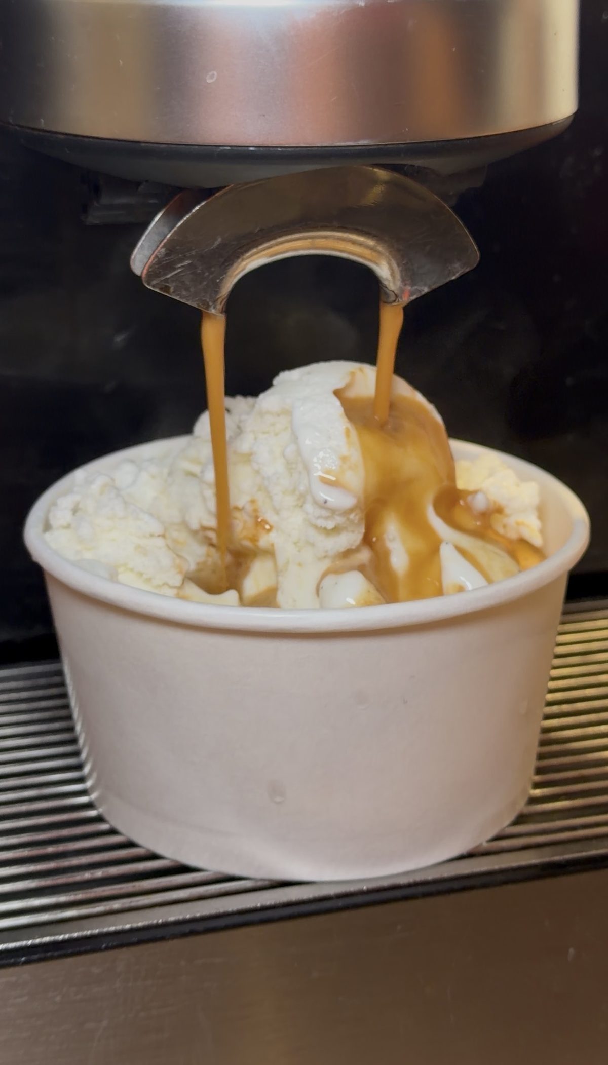Espresso pouring from the machine onto a scoop of vanilla ice cream in a paper cup at CR Coffee Shop