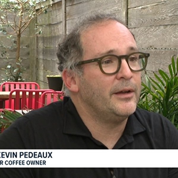 Kevin Pedeaux seated on the CR Coffee patio during a WWL Louisiana television interview, with a lower-third reading Kevin Pedeaux, CR Coffee Owner