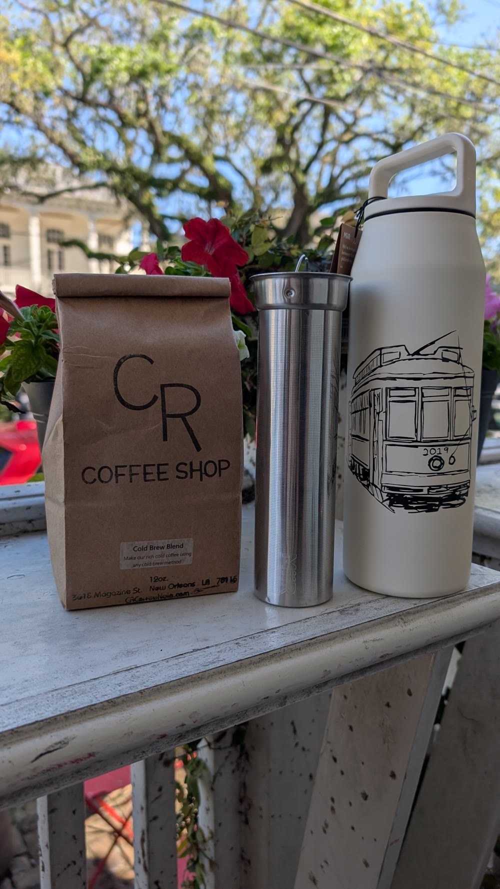 A bag of CR whole bean coffee with a cold brew filter and streetcar bottle on the Magazine Street porch